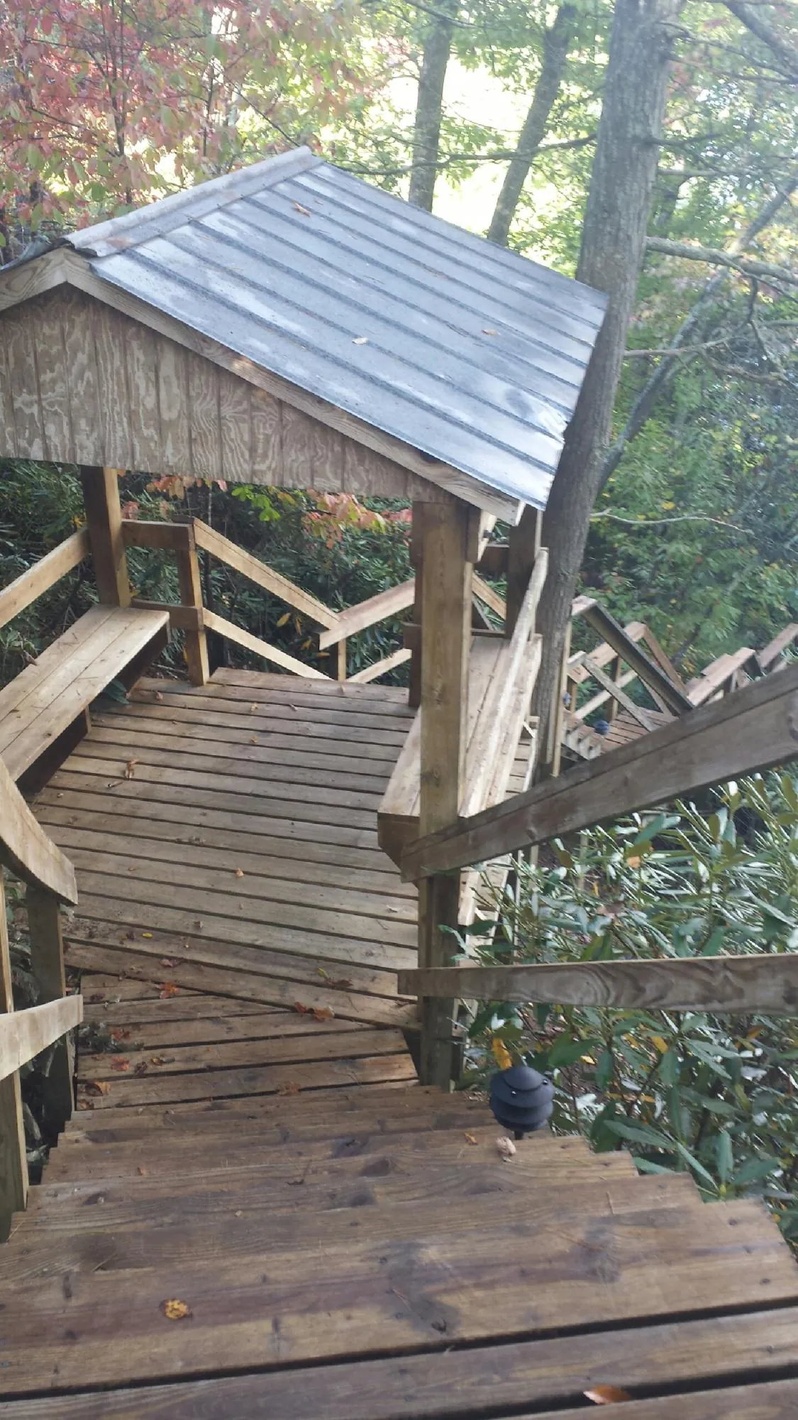 Metal roofed shelter over wooden steps on a wooded walkway — Skylight Repair & Installation work by our crew in Washburn